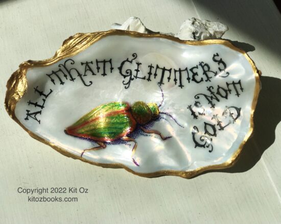 Gold and green beetle painted inside an oyster shell with the quotation: All that glitters is not gold.