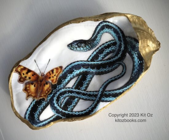 blue and turquoise snake and orange and brown butterfly, painted inside an oyster shell with gold trim.