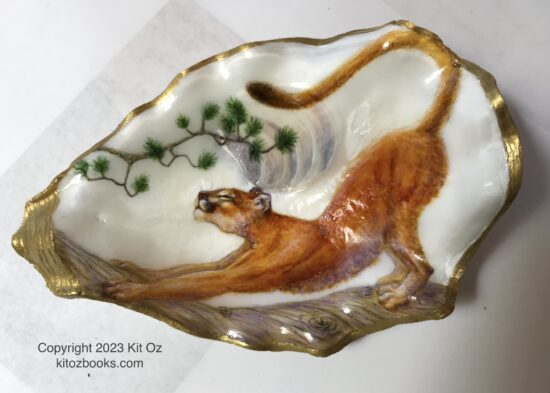 mountain lion stretching on a log, painted inside an oyster shell