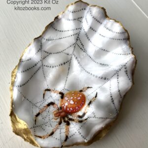 orange spider and silver web painted on an oyster shell.